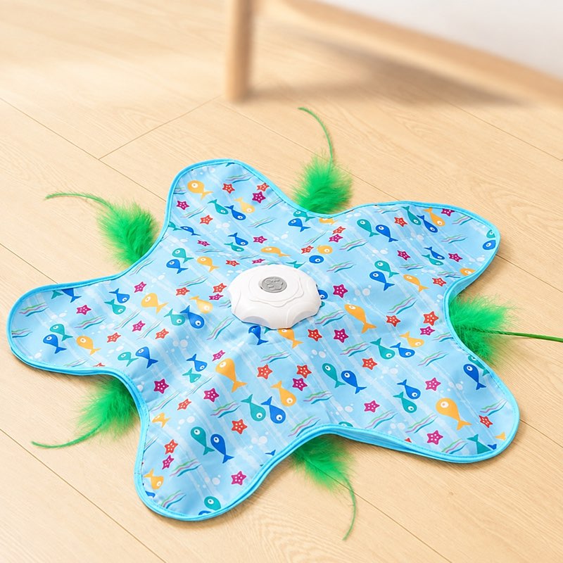 Teaser toy play mat on the floor with green feather wands poking out at the edges